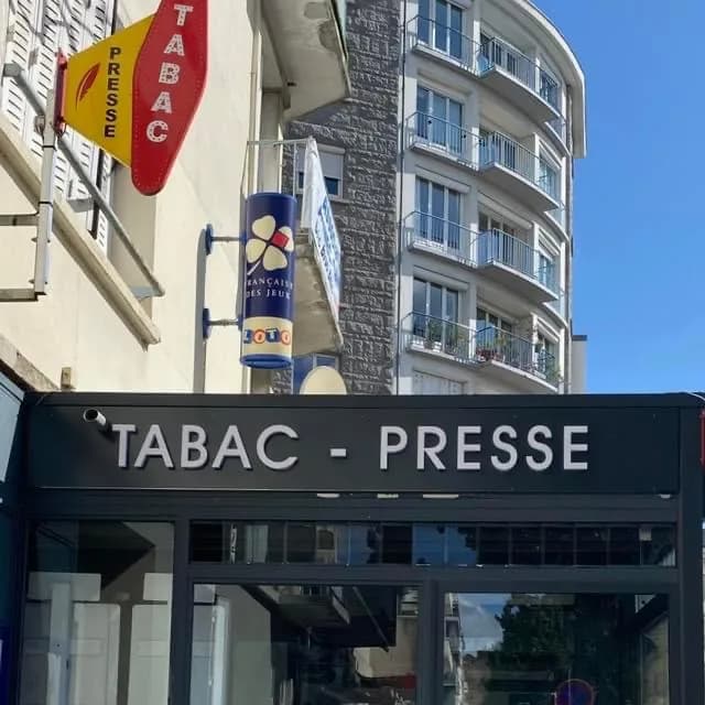 Enseigne « Tabac – Presse » sous la carotte rouge du buraliste et le totem Loto de la Française des Jeux.