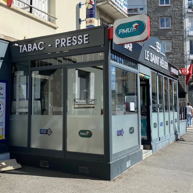 L'avancée vitrée « Tabac – Presse » à l'angle, sous l'enseigne PMU et le totem de la Française des Jeux.