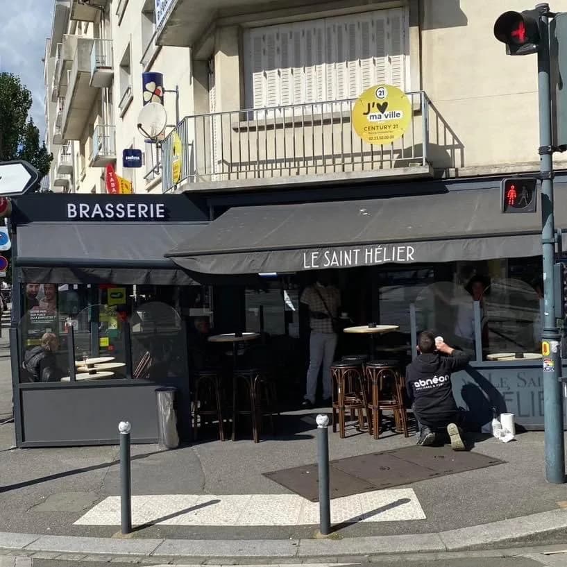 La terrasse du Saint-Hélier à l'angle de la rue, tables hautes et tabourets sous les auvents.